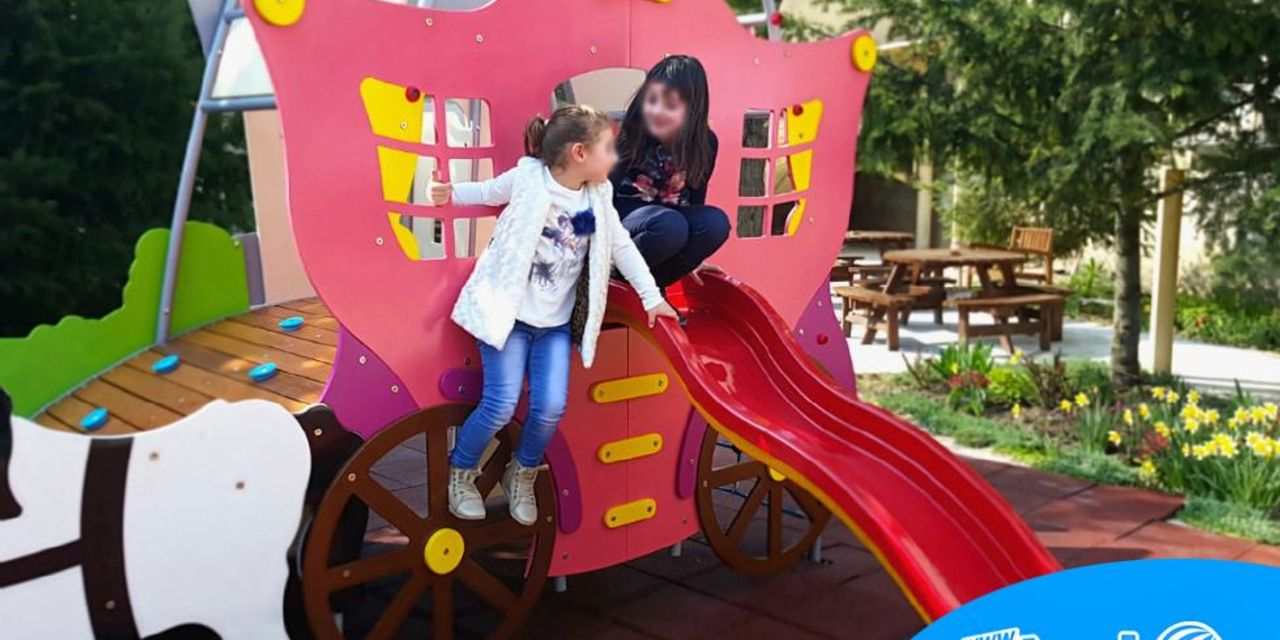 Complex de joacă în formă de căruță cu cai, cu tobogan și platformă de cățărare, pe o terasă HoReCa, cu doi copii care se joacă. Complex de joacă în formă de căruță cu cai, cu tobogan și platformă de cățărare, pe o terasă HoReCa, cu doi copii care se joacă.