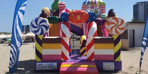 Castel gonflabil colorat cu tematică candy amplasat la un eveniment pe plajă Castel gonflabil colorat cu tematică candy amplasat la un eveniment pe plajă