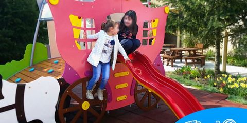 Complex de joacă în formă de căruță cu cai, cu tobogan și platformă de cățărare, pe o terasă HoReCa, cu doi copii care se joacă. Complex de joacă în formă de căruță cu cai, cu tobogan și platformă de cățărare, pe o terasă HoReCa, cu doi copii care se joacă.
